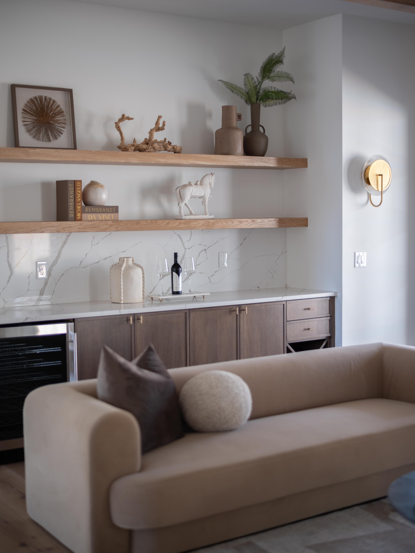 Wet bar lounge with styled oak shelves and a curved bouclé sofa