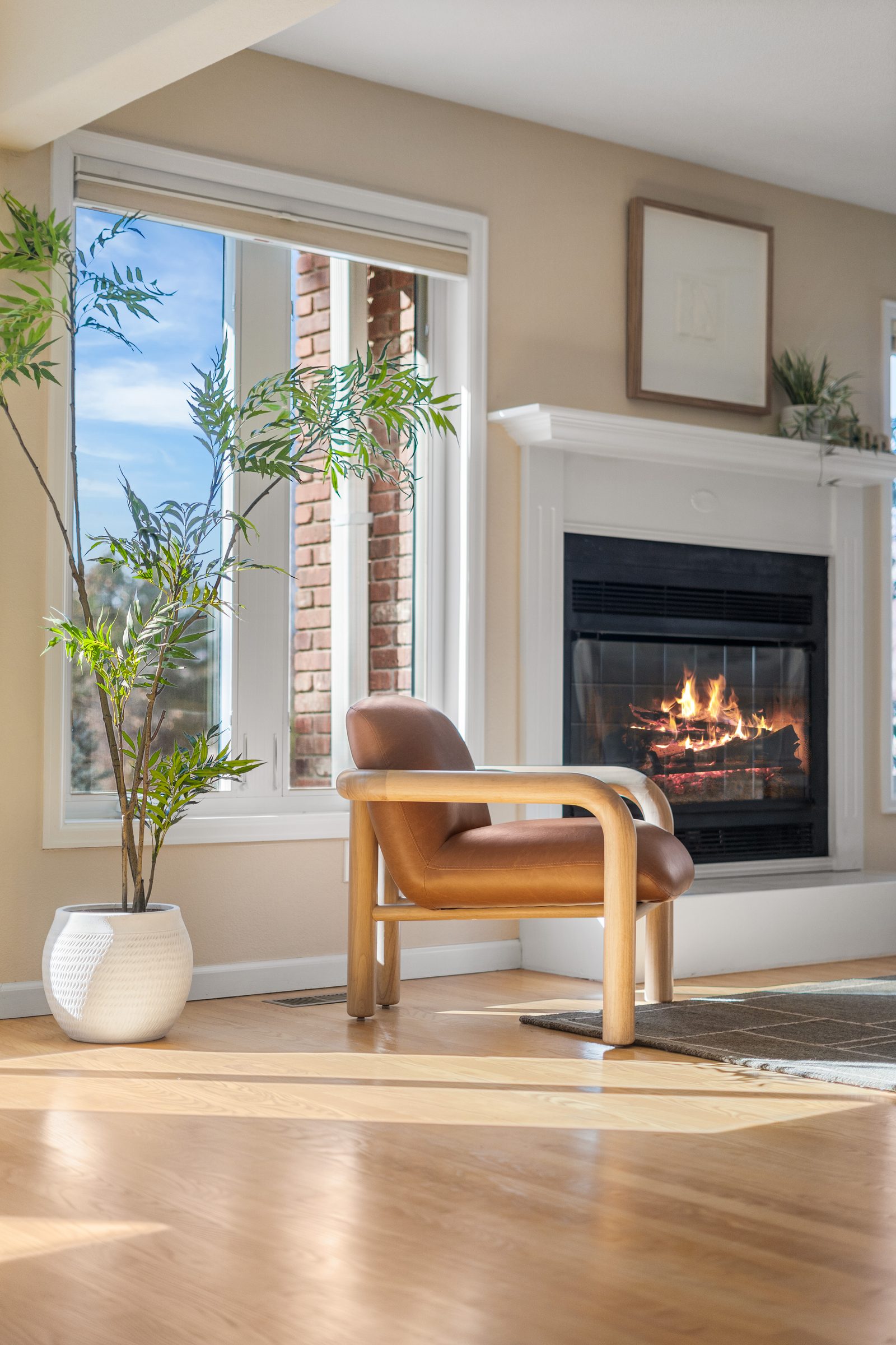 Living room with a wood chair beside a lit fireplace